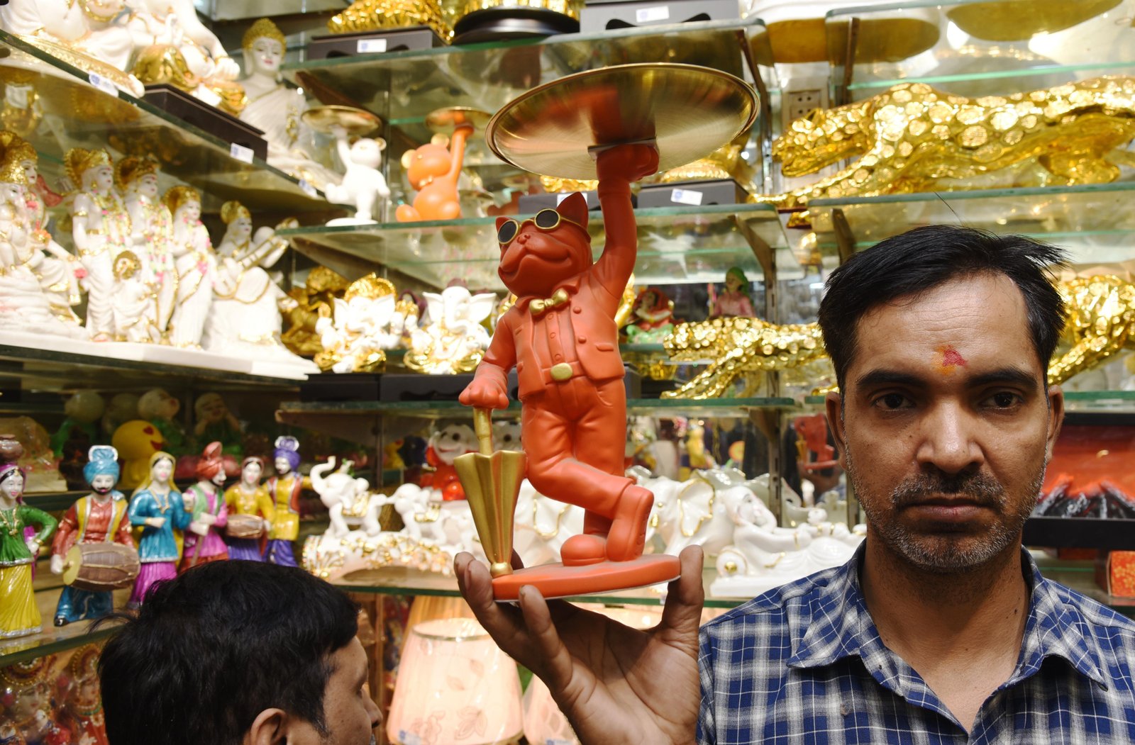 A shopkeeper selling a modern avtaar of Lord Hanuman in a shop in old Delhi